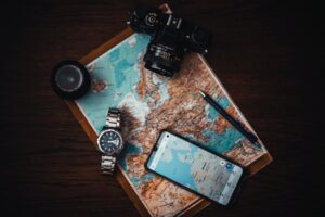 Imagem representando viajantes planejando um roteiro de viagem perfeito com um mapa, guia de viagem e câmera fotográfica.